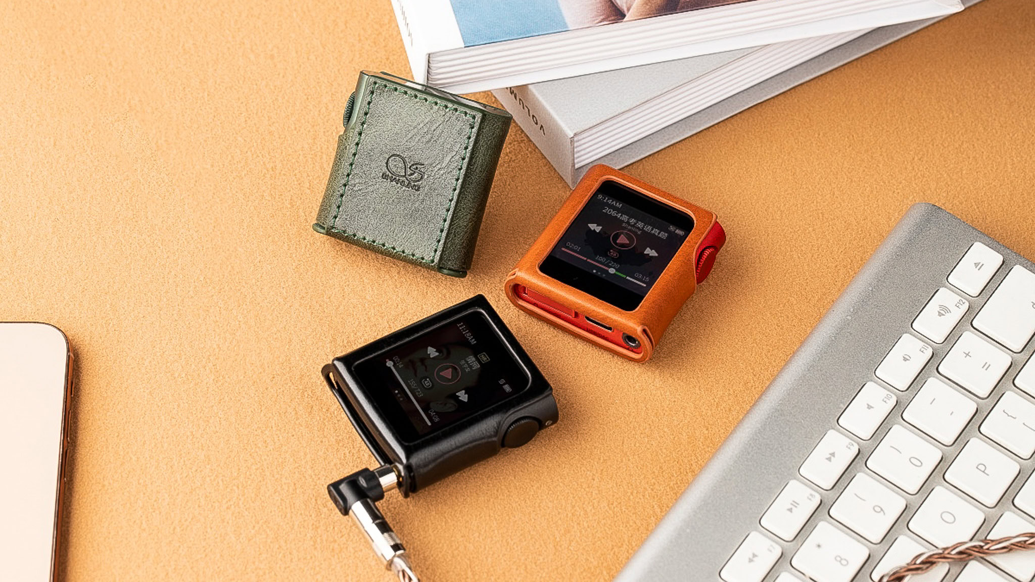 Three Shanling M0 Pro compact DAPs on a desk with a keyboard and books